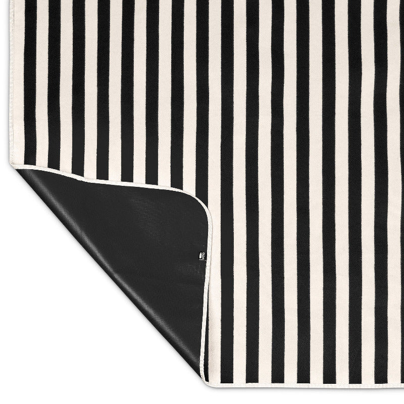 Black and white striped picnic blanket with a corner folded over, showing waterproof p.backing